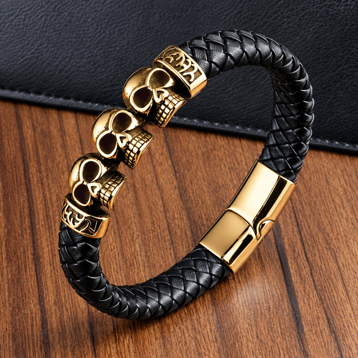 Svart armband av läder med guldfärgade dödskallar och detaljer av rostfritt stål