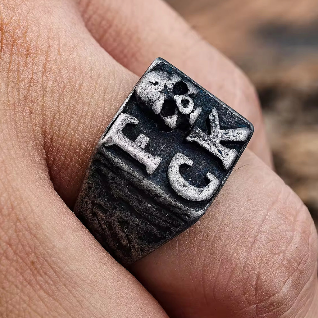 Svart klackring med dödskalle och texten fuck på klacken