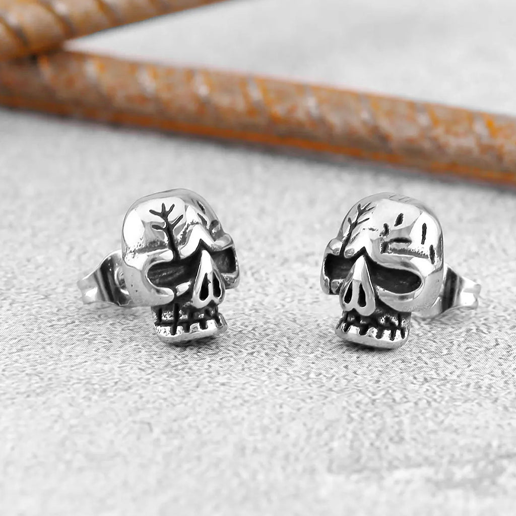 Silverfärgade ear studs föreställande en dödskalle med sprickor