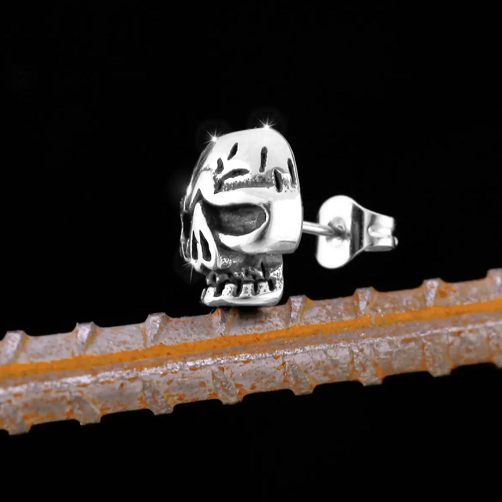 Silverfärgade ear studs föreställande en dödskalle med sprickor på kraniet