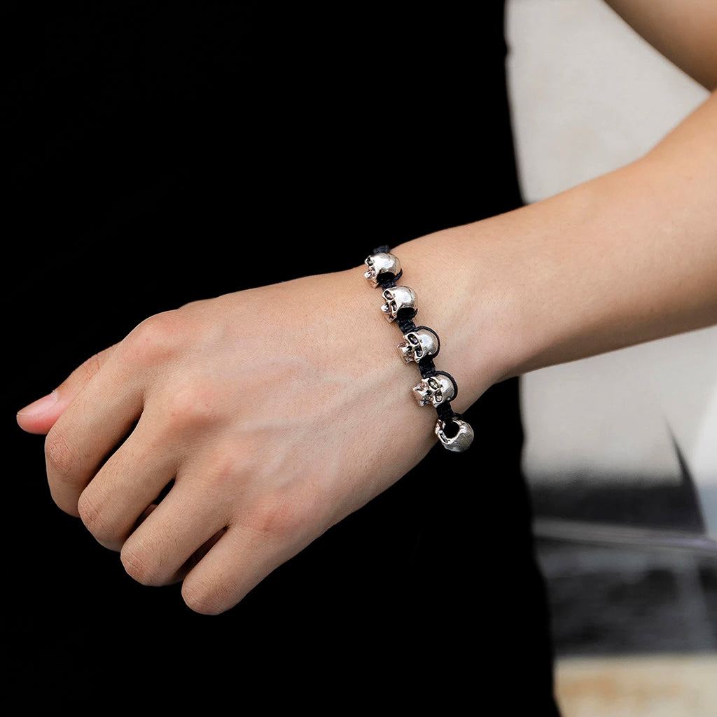 Svart flätat reparmband med silverfärgade döskallar