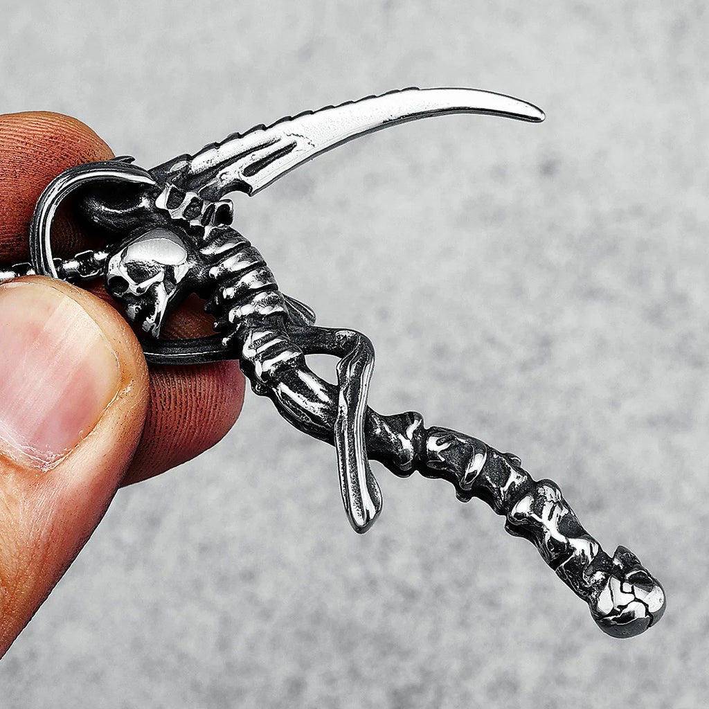 Silverfärgat hängsmycke föreställande en lie med skallar