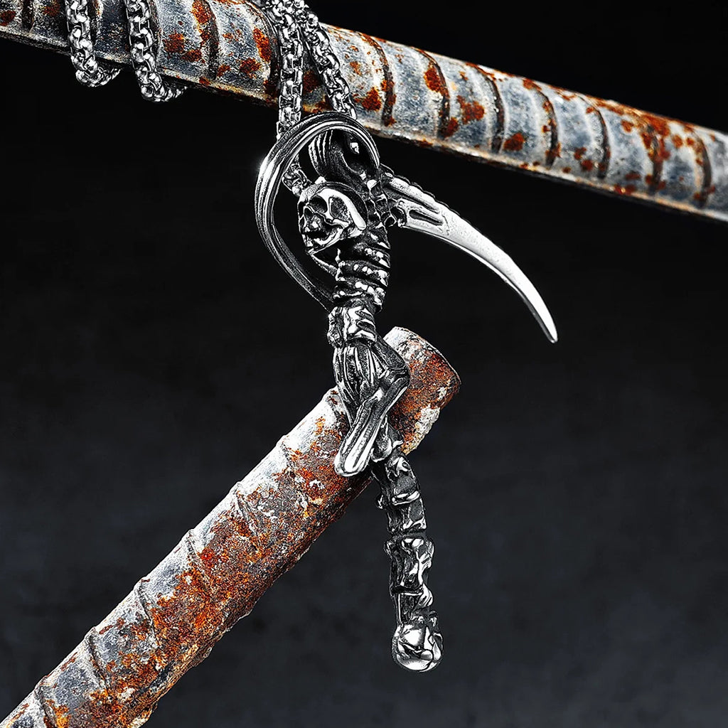 Silverfärgat hängsmycke föreställande en lie med döskallar
