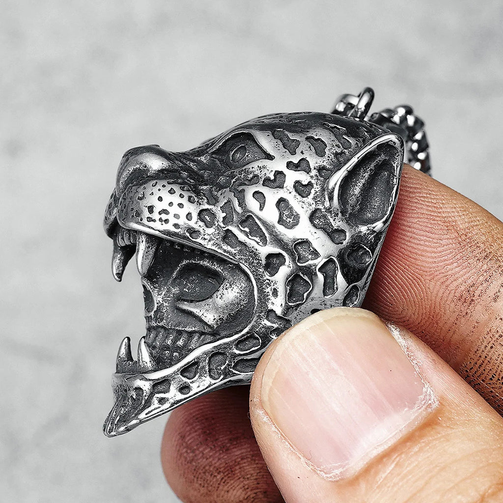 Stålfärgat hängsmycke föreställande ett rovdjur med en dödskalle innanför käkarna