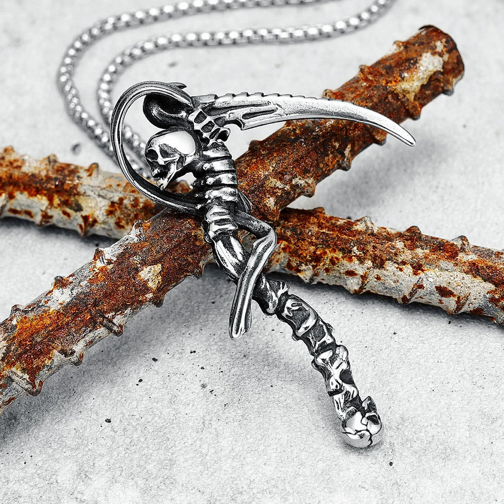 Silverfärgat hängsmycke föreställande en lie med kranium