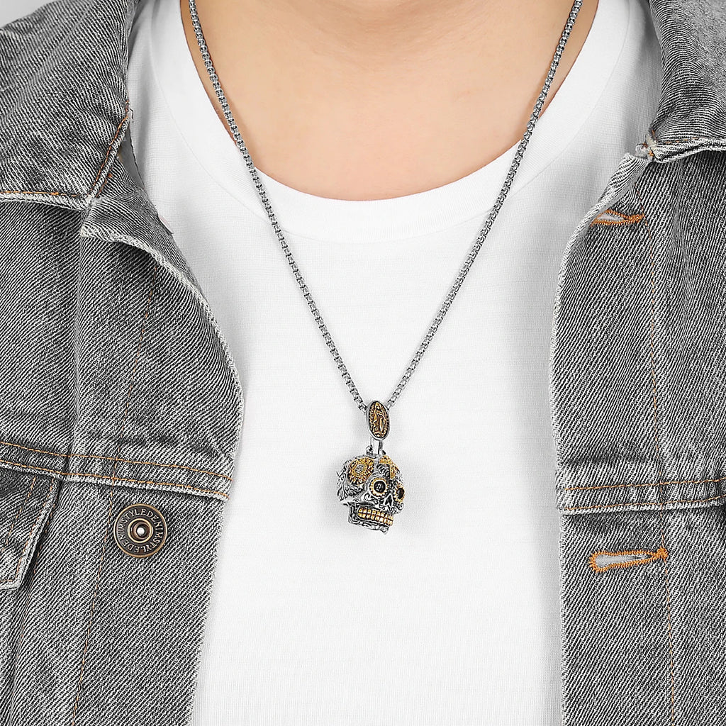 Silverfärgat hängsmycke föreställande en mexikansk calavera skalle med guldfärgade detaljer