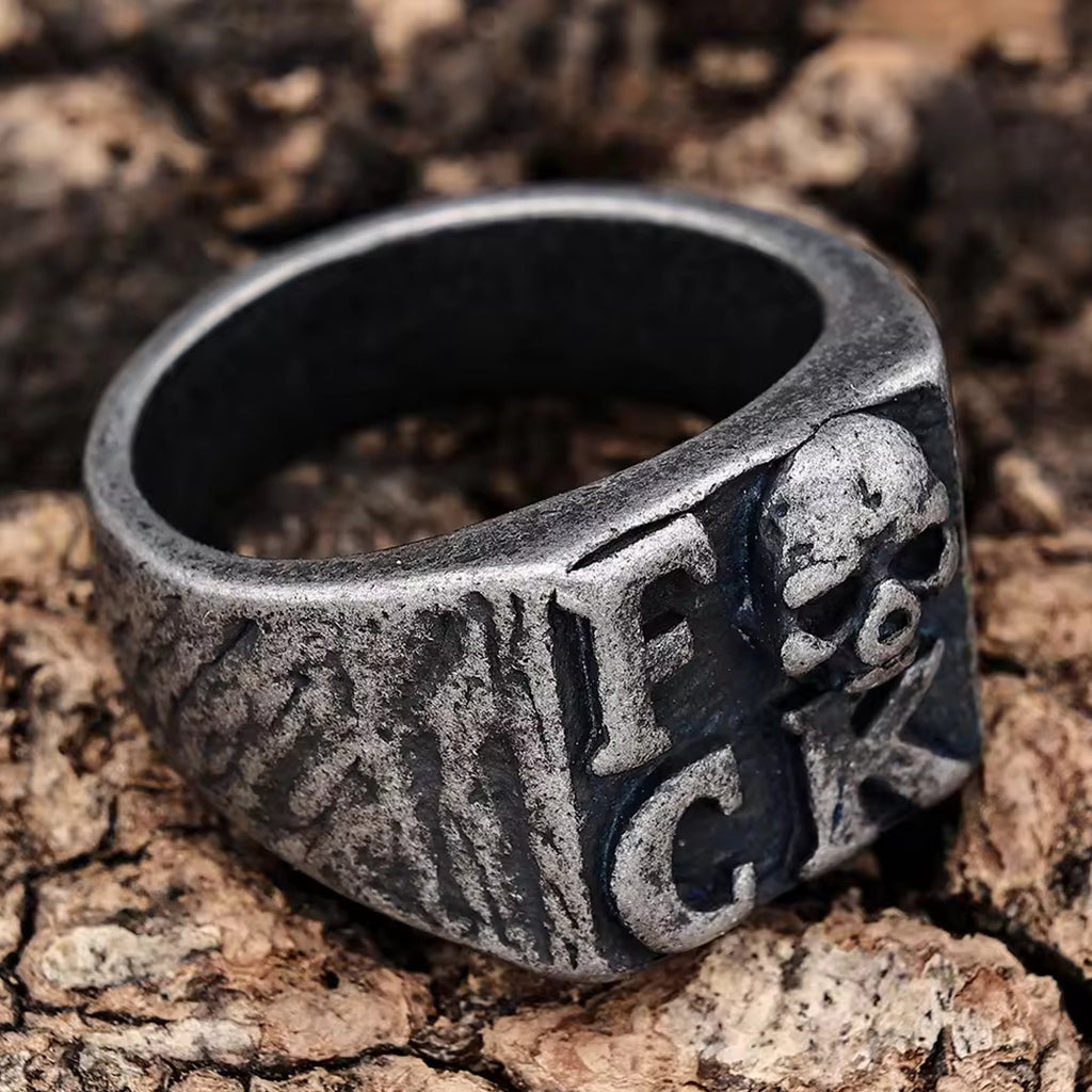 Svärtad klackring med dödskalle och texten fuck på klacken