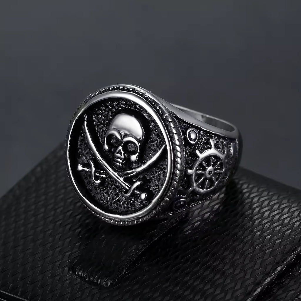 Silverfärgad dödskallering i rostfritt stål med två korsade svärd på klacken