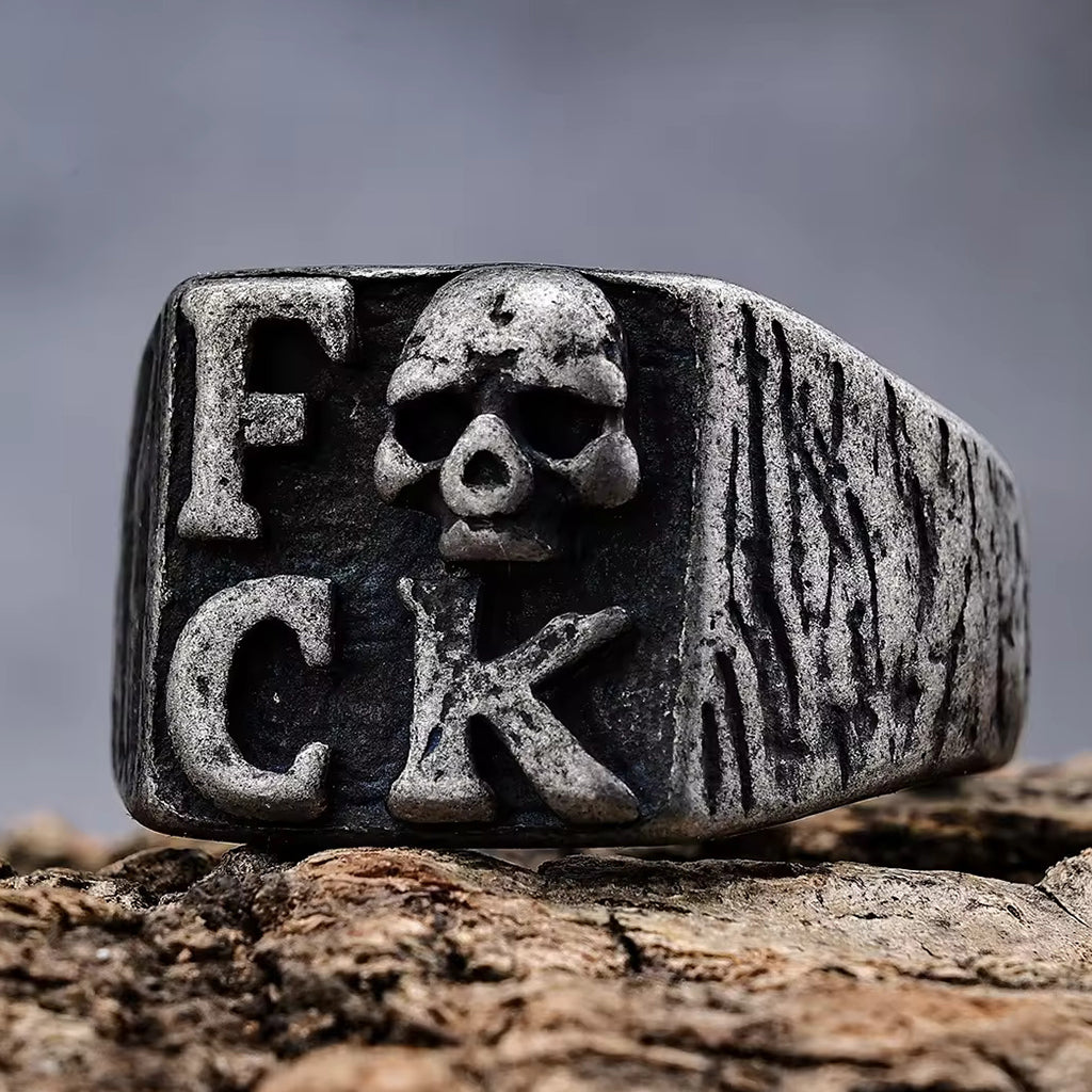 Svart klackring med dödskalle och texten fuck på klacken
