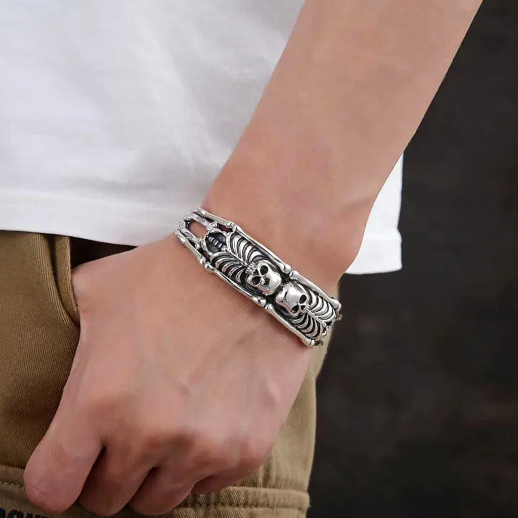 Silverfärgat manschettarmband av sterling silver med två dödskallar