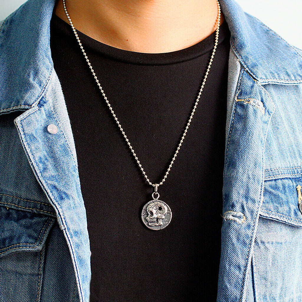 Hängsmycke av sterling silver föreställande ett cirkelformat mynt avbildande en dödskalle med ett kulhål i skallen