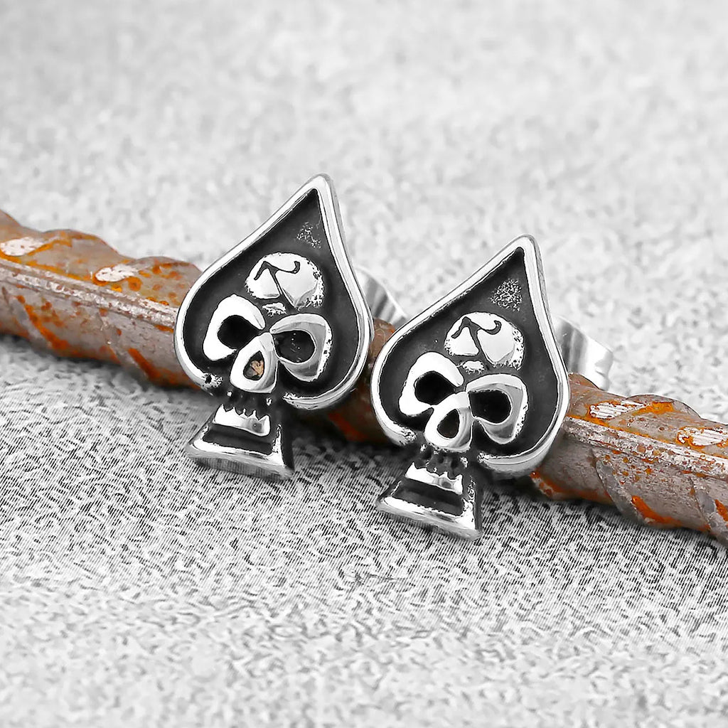 Silverfärgade örhängen formade som spader ess med en dödskalle i mitten
