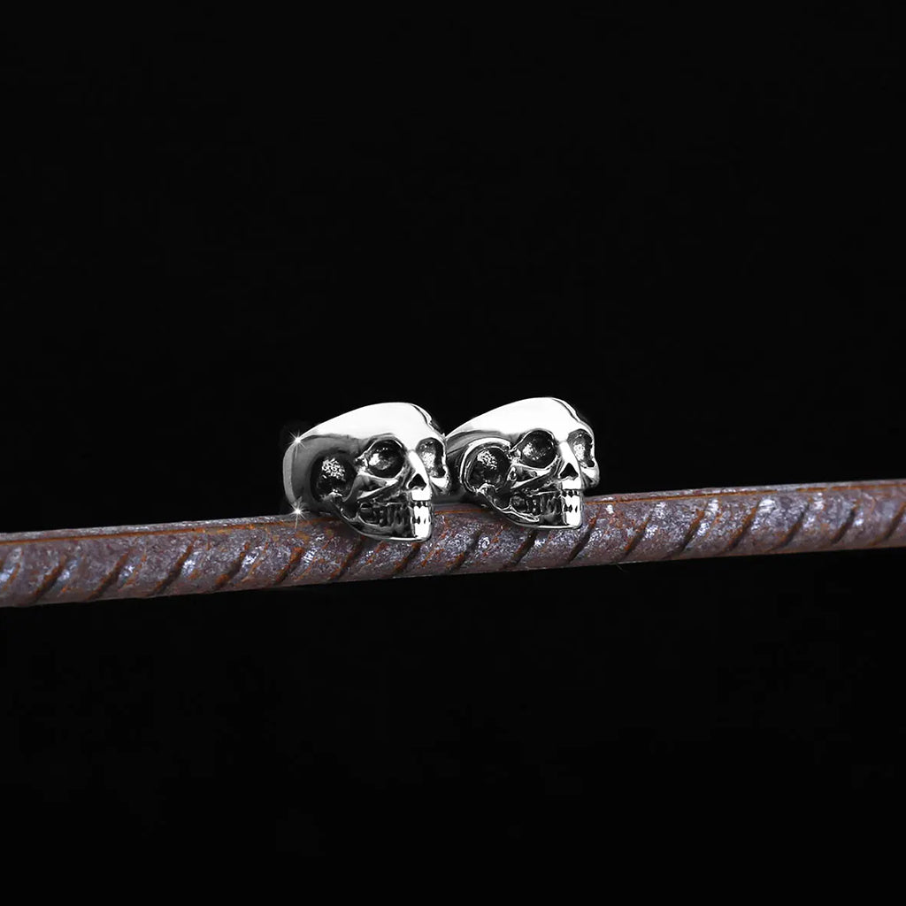 Silverfärgade öronsmycken som är formade som dödskallar