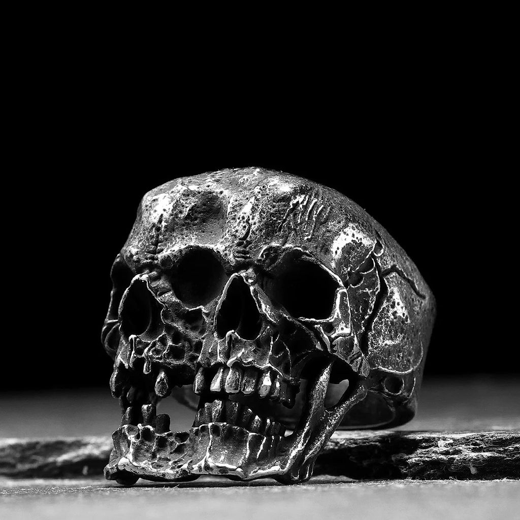 Ring i svärtat stål som visar två dödskallar som sitter ihop