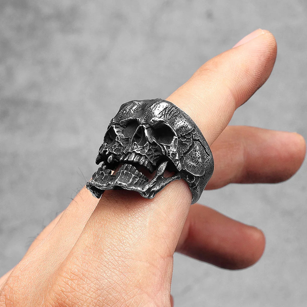 Ring i svärtat stål som visar två dödskallar som sitter ihop