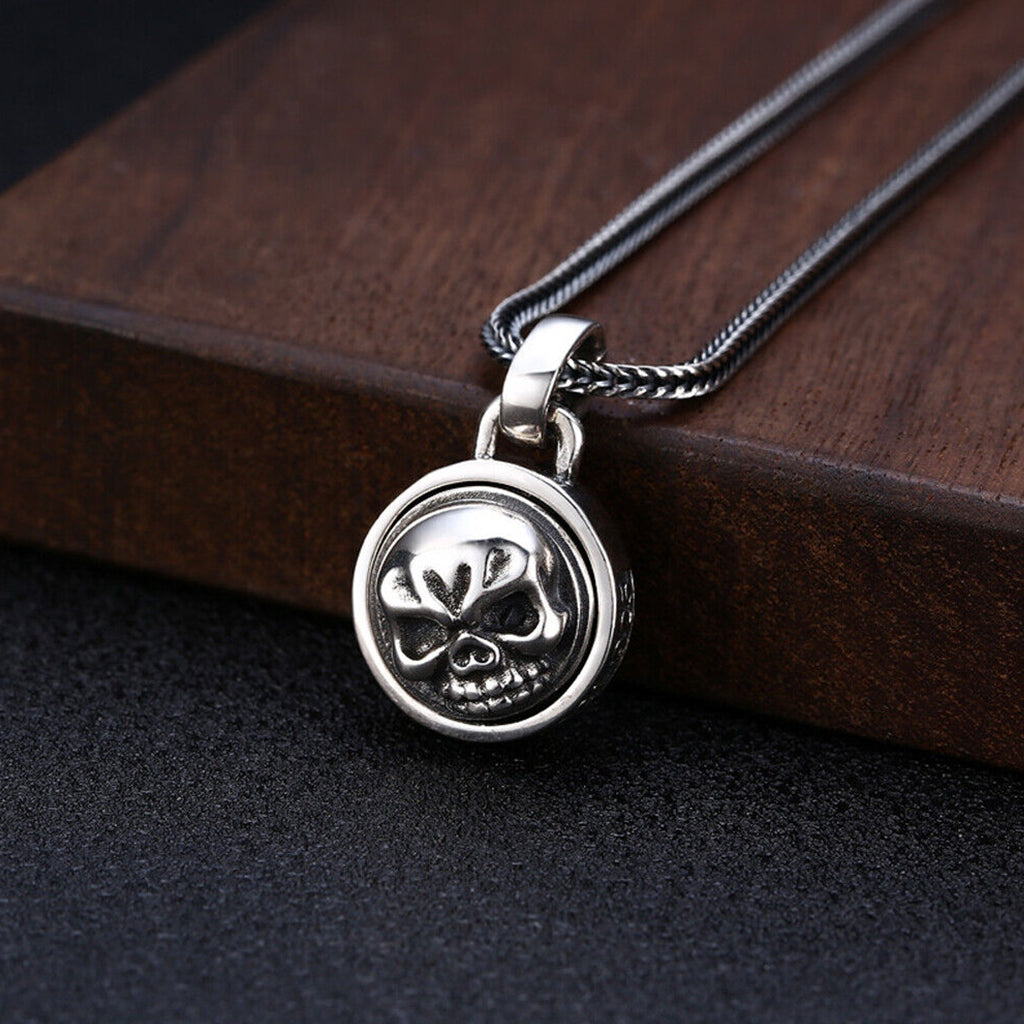 Dubbelsidigt hänge av sterlingsilver, formgivet som ett runt smycke med en vridbar dödskalle