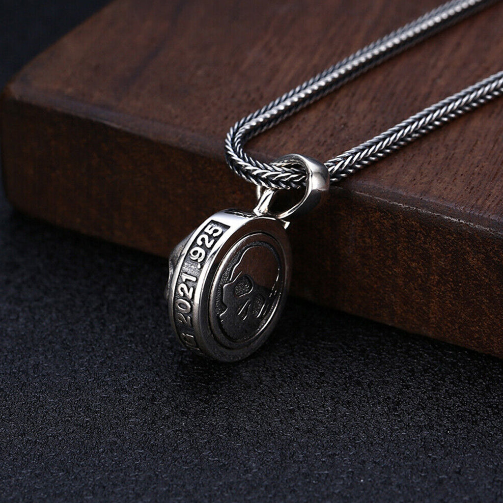 Dubbelsidigt hängsmycke av sterlingsilver, formgivet som ett runt smycke med en roterbar dödskalle