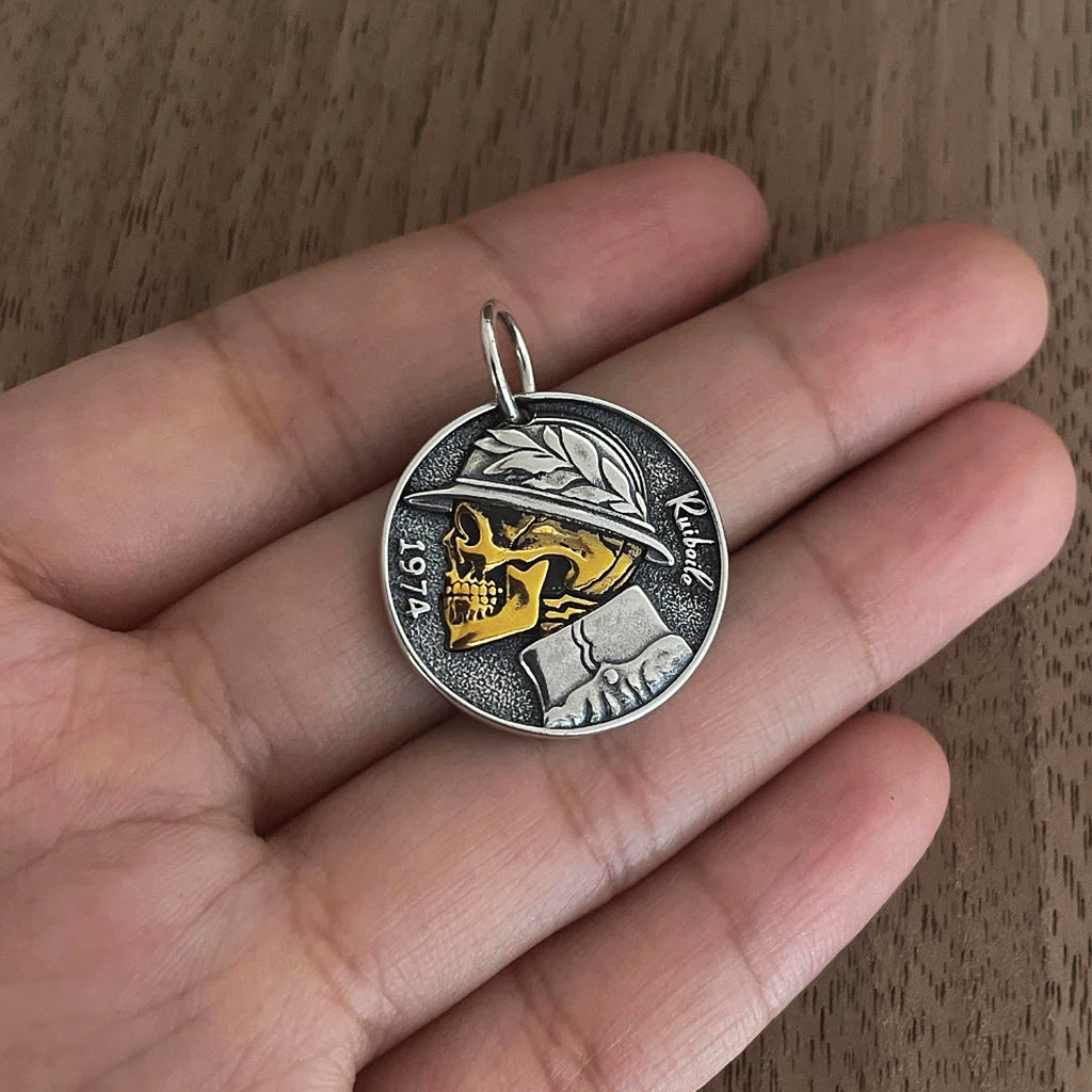 Runt smycke av sterling silver med en guldfärgad dödskalle