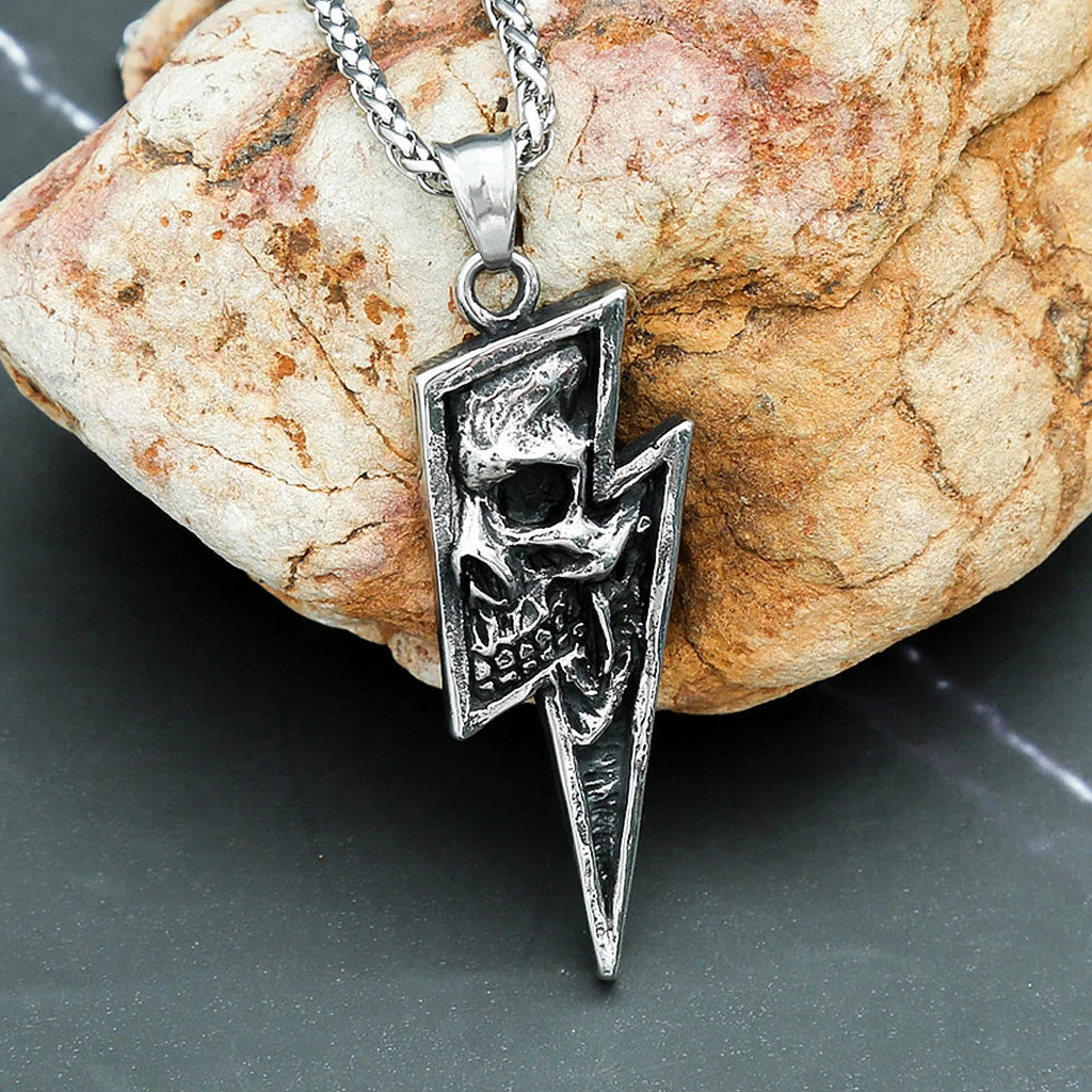 Silverfärgat smycke föreställande en blixt med en dödskalle invändigt