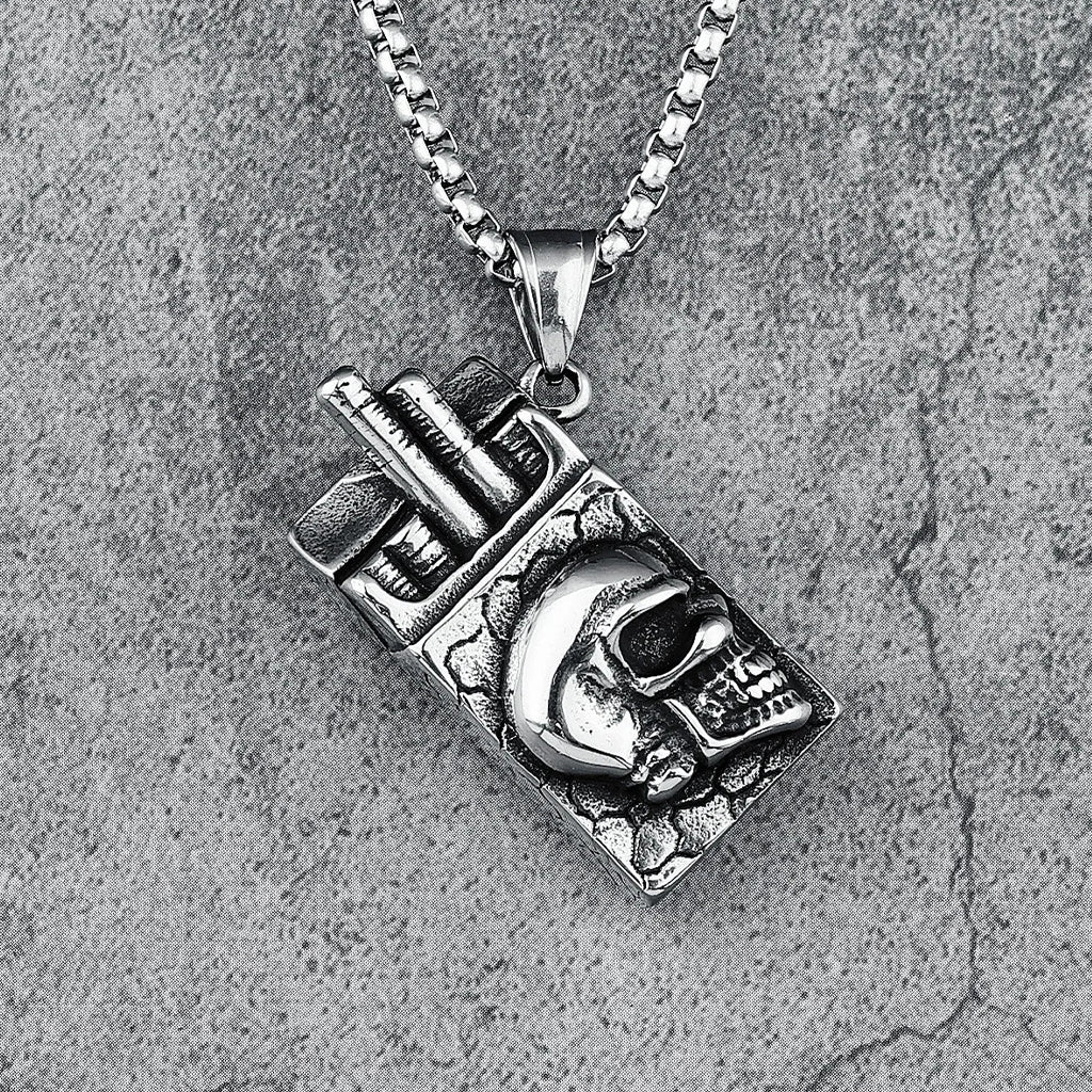 Silverfärgat smycke föreställande ett cigarettpaket med en dödskalle på