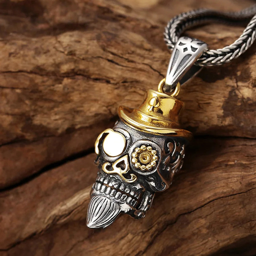 Silverfärgat sterlingsilver smycke föreställande en dödskalle med guldfärgad hatt, mustasch och monokel