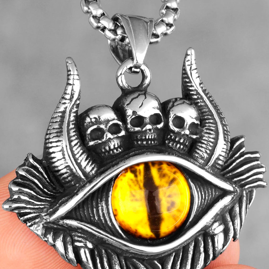 Silverfärgat smycke föreställande tre små dödskallar och ett gult djävulsöga med demonhorn