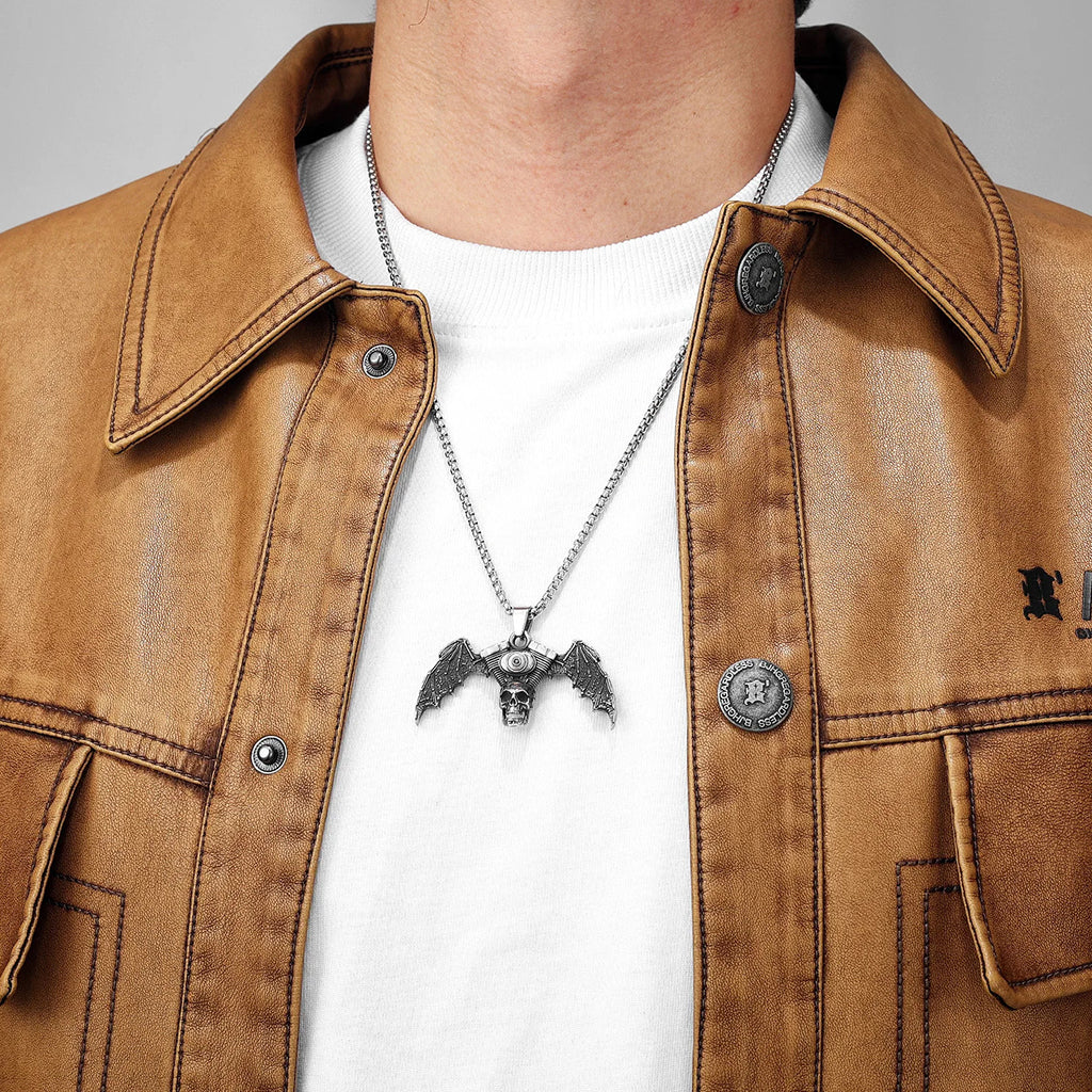 Silverfärgat smycke föreställande en motorcykelmotor med en dödskalle och fladdermusvingar