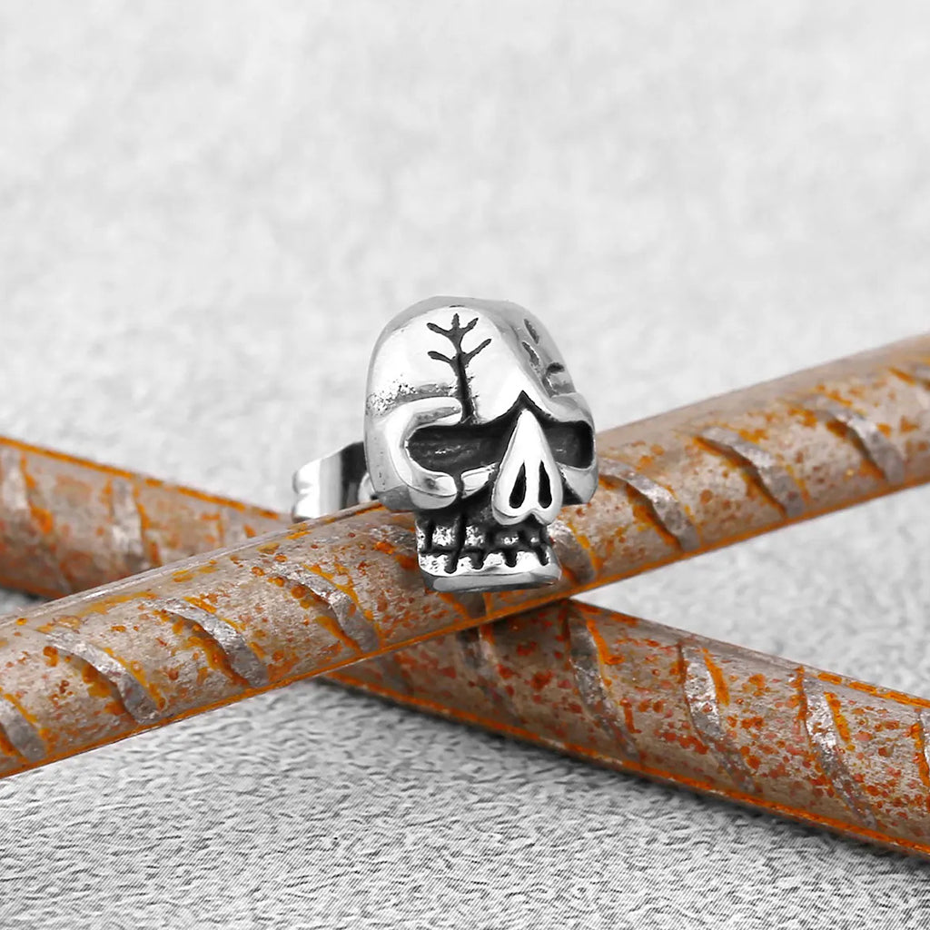 Silverfärgade öronstift föreställande en dödskalle med sprickor på kraniet