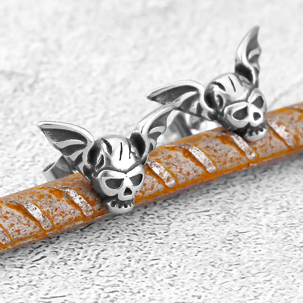 Silverfärgade stiftörhängen föreställande en dödskalle med fladdermusvingar