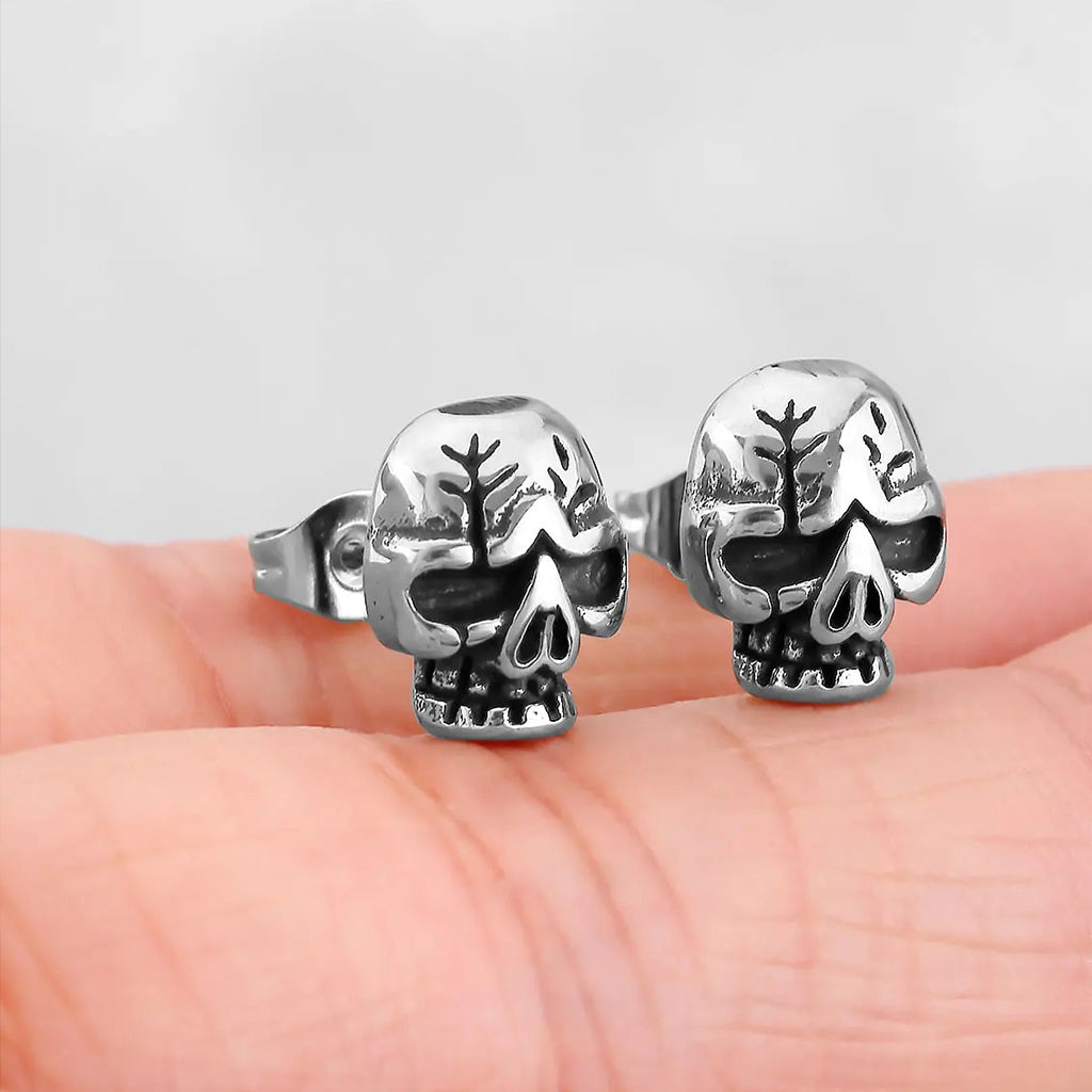 Silverfärgade stiftörhängen föreställande en dödskalle med sprickor på kraniet