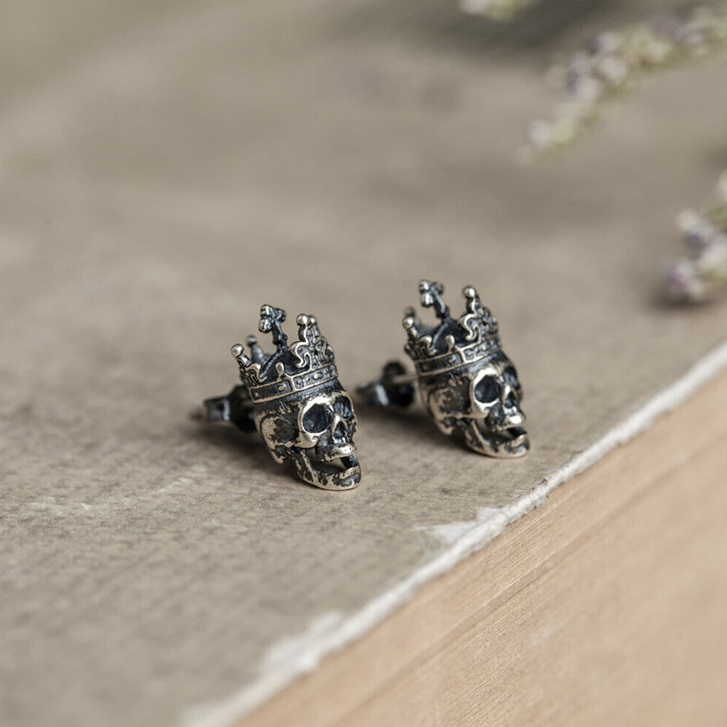 Silverfärgade studs-örhängen i sterling silver föreställande en dödskalle med en krona på skallen