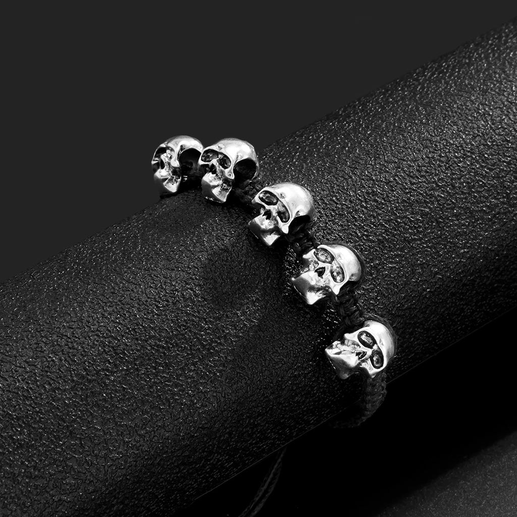 Svart flätat reparmband med silverfärgade dödskallar