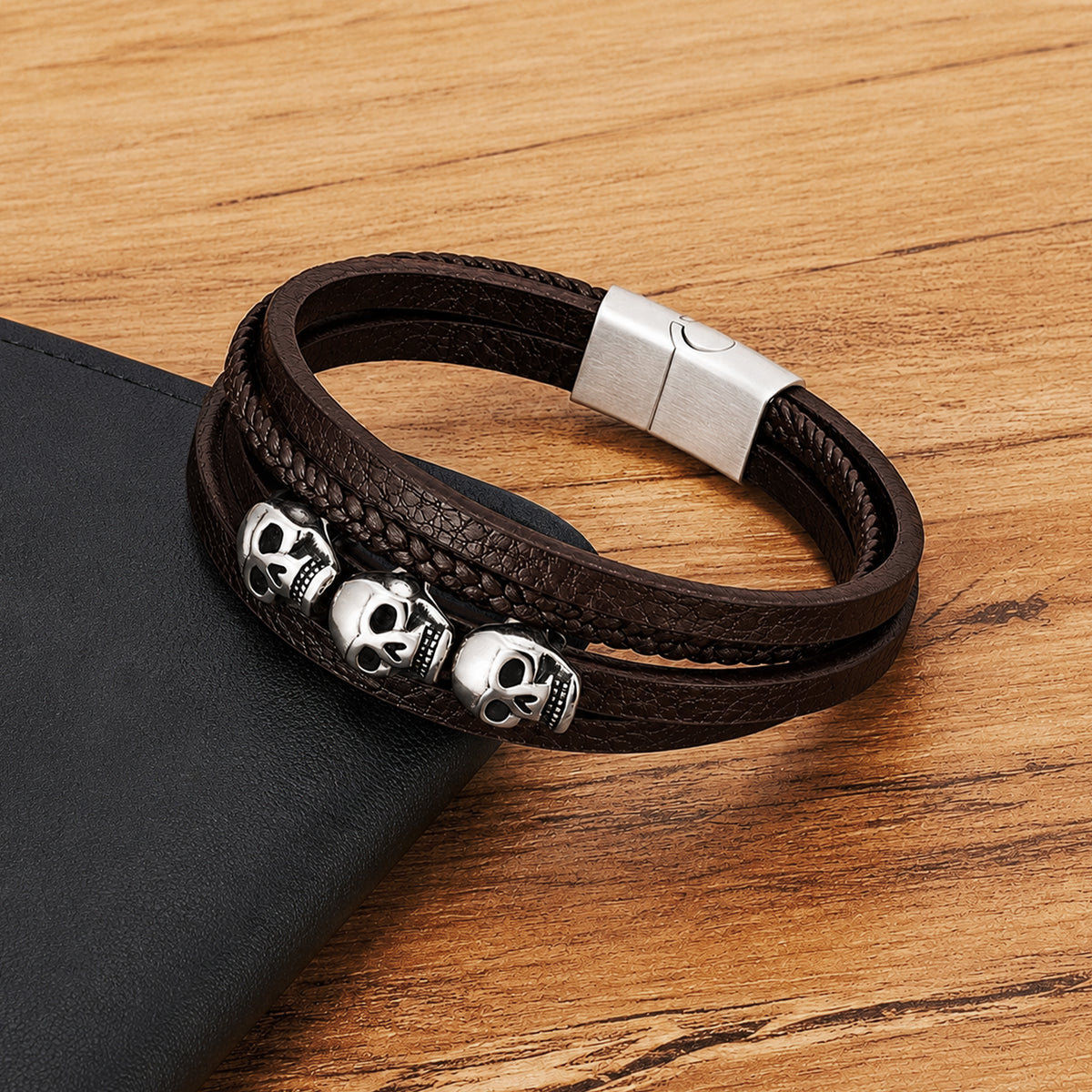 Brunt läderarmband med tre dekorativa dödskallar av rostfritt stål