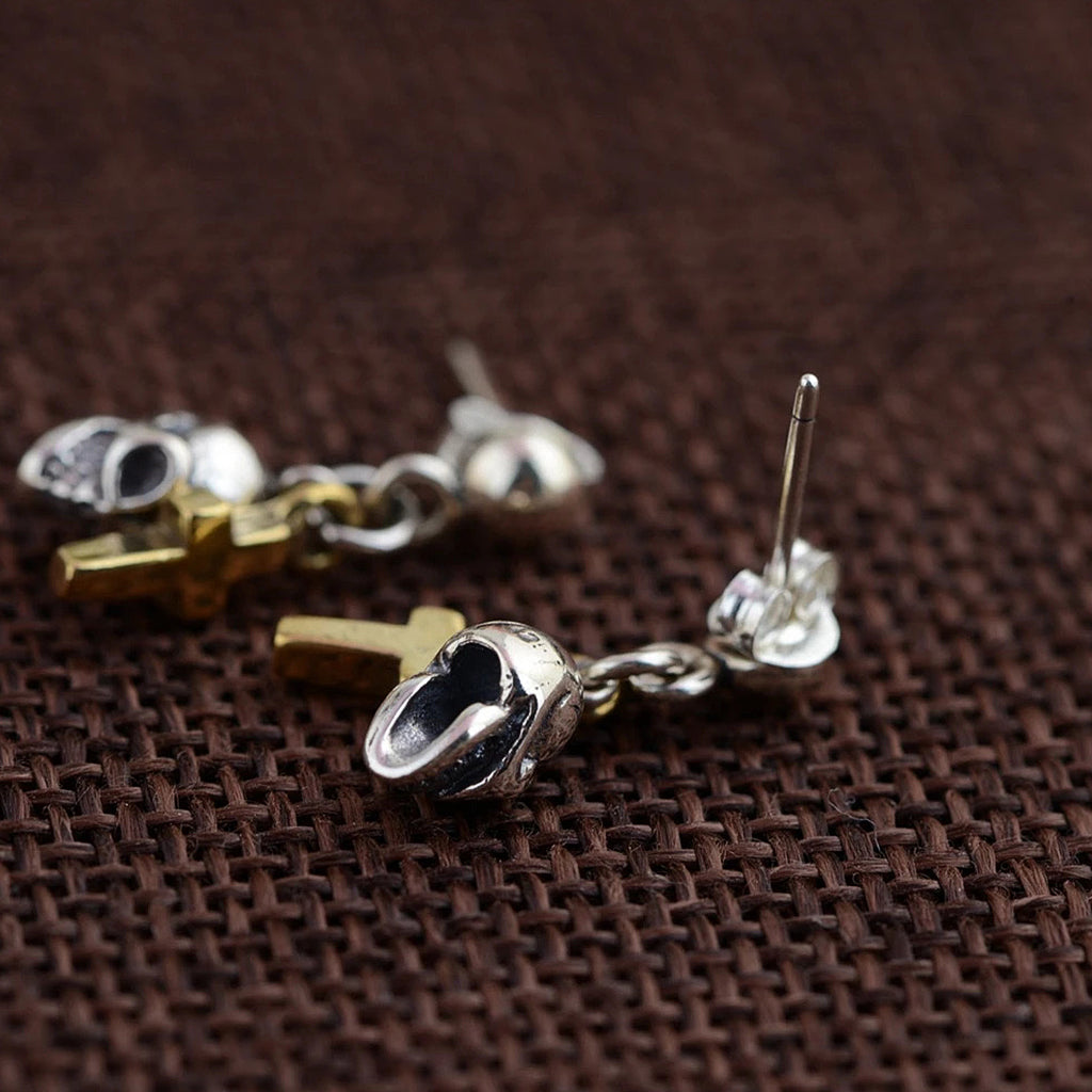 Ear studs-örhängen i sterlingsilver föreställande en dödskalle och ett guldfärgat kors