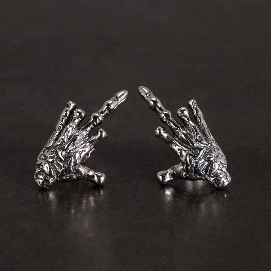 Silverfärgade ear studs-örhängen av silver föreställande en demonisk skeletthand som ger fingret