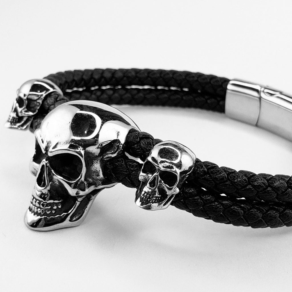 Mörkt flätat armband i läder med tre silverfärgade skallar