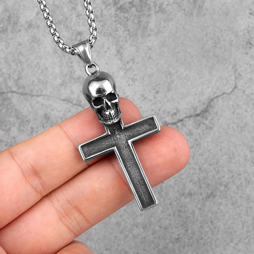 Silverfärgat smycke föreställande ett latinskt kors med en dödskalle upptill