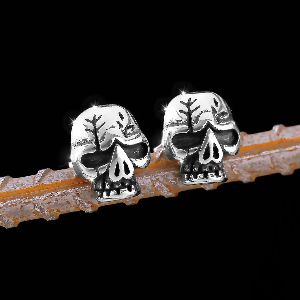 Silverfärgade örhängen föreställande en dödskalle med sprickor på kraniet