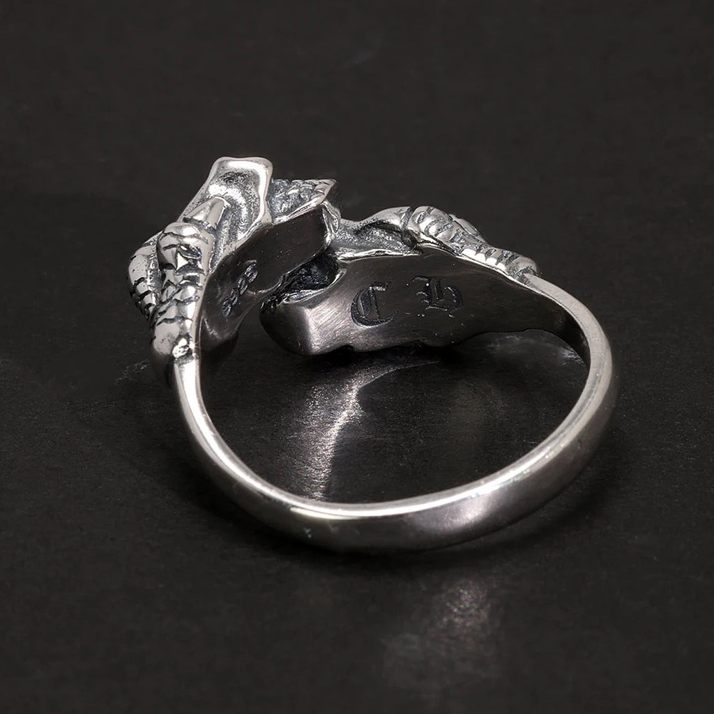 Silverfärgad ring av sterling silver föreställande två dödskallar som hålls fast av örnklor