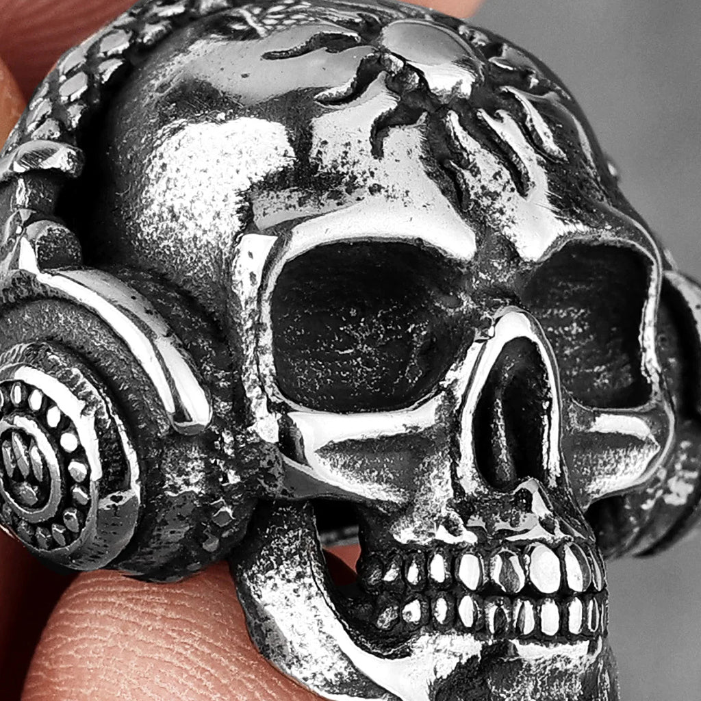 Silverfärgat smycke föreställande en dödskalle med hörlurar