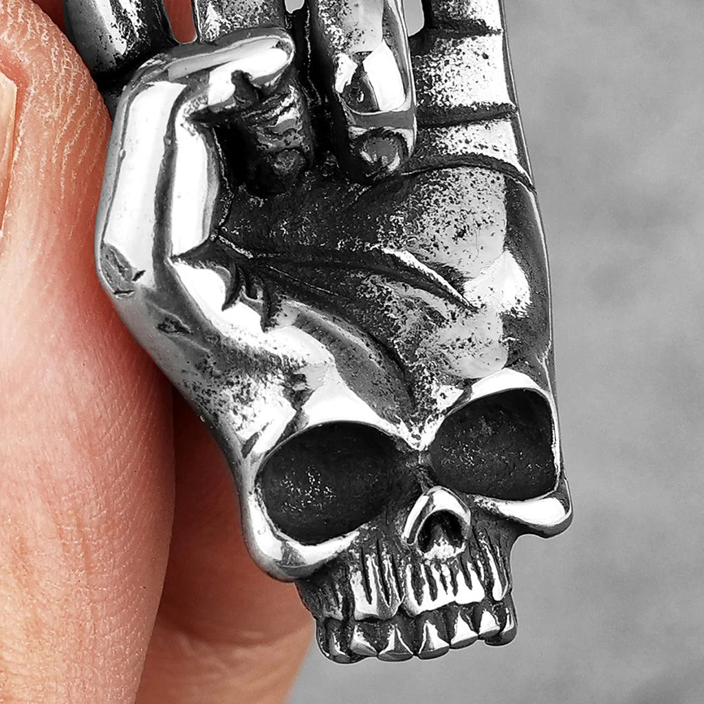 Silverfärgat hängsmycke föreställande en dödskalle-hand som gör rock'n'roll-tecknet (corna)