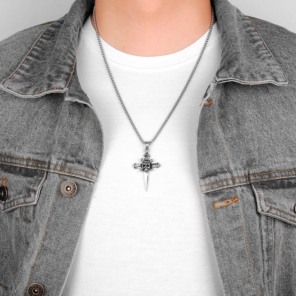 Silverfärgat smycke föreställande ett spik-kors med en döskalle med korslagda benknotor i centrum