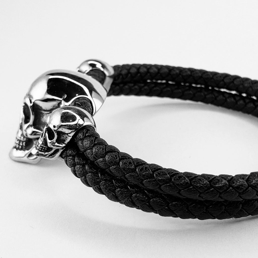 Mörkt flätat armband i läder med tre silverfärgade döskallar