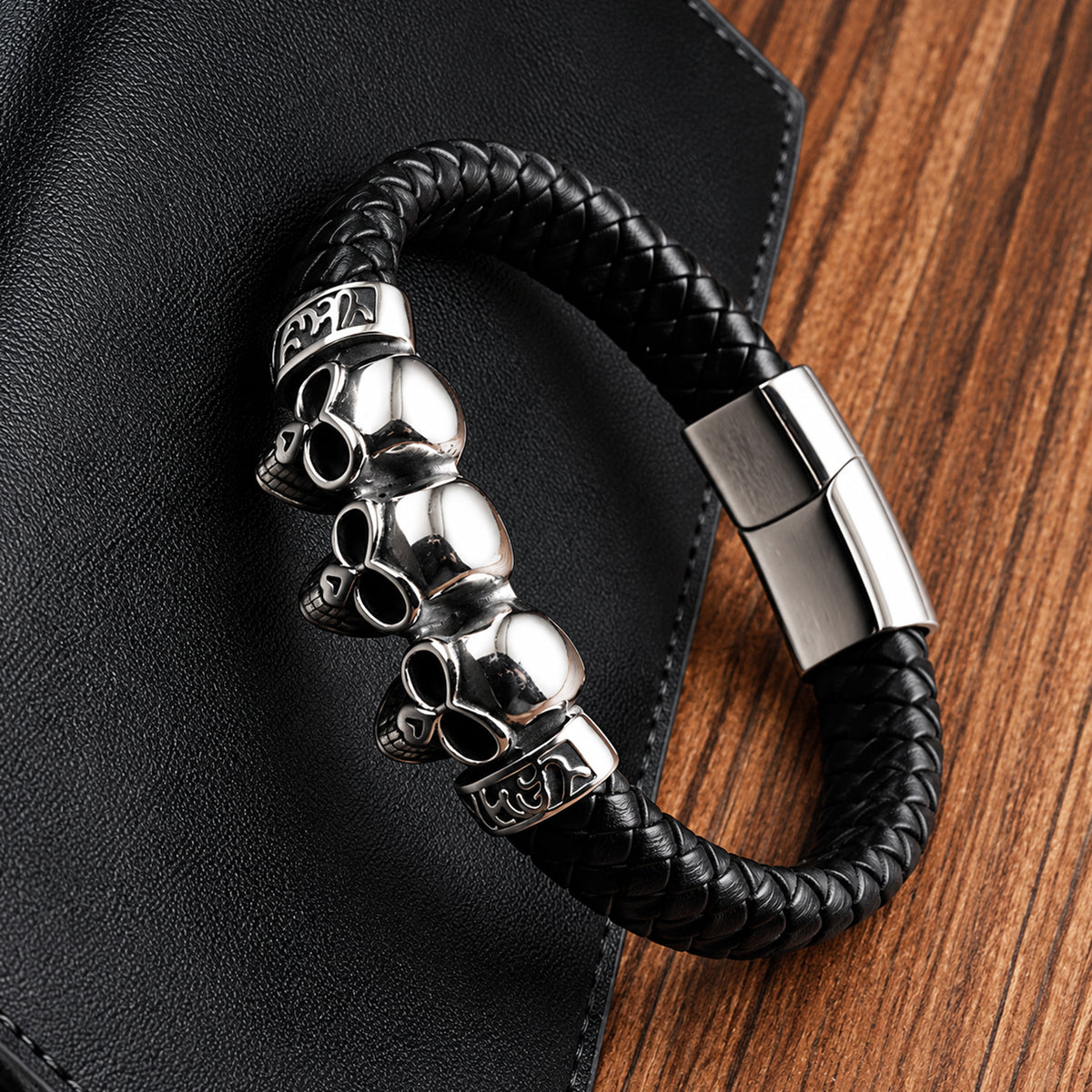 Svart flätat läderarmband med tre silverfärgade dödskallar av stål