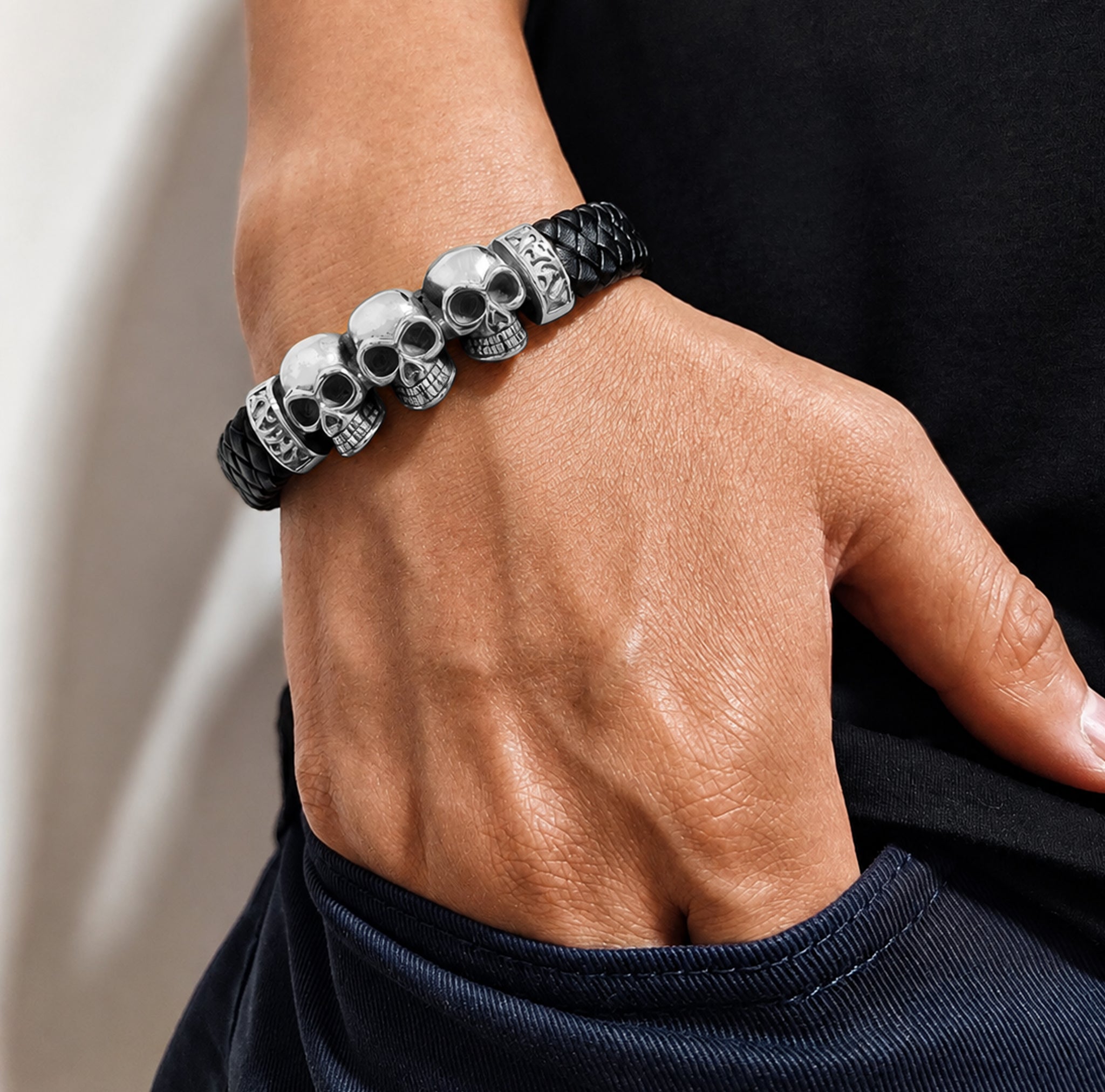 Svart flätat läderarmband med tre silverfärgade dödskallar av stål
